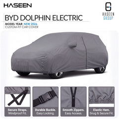 A gray car cover fitted over a car, shown on a white background with HASEEN branding and feature callouts. The image includes text reading 'BYD DOLPHIN ELECTRIC' and 'MODEL YEAR: NEW 2026 CUSTOM-FIT CAR COVER,' plus four small inset detail images at the bottom showing straps, buckle, zippers, and hem.