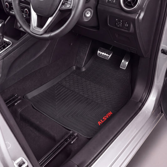 Black Alsin floor mats installed in a car's driver's side footwell, shown with the door open and interior visible.