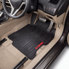 A pair of black rubber car floor mats with red 'CIVIC' branding, shown installed in the front of a beige Honda Civic interior.