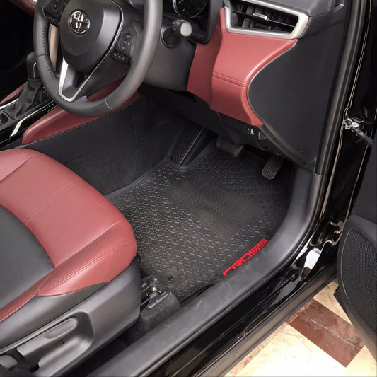 A car interior with black and burgundy leather seats, a black steering wheel with a silver Kia logo, and black textured floor mats with red 'PROSE' branding.