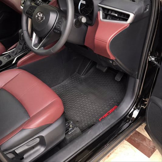 A car interior with black and burgundy leather seats, a black steering wheel with a silver Kia logo, and black textured floor mats with red 'PROSE' branding.