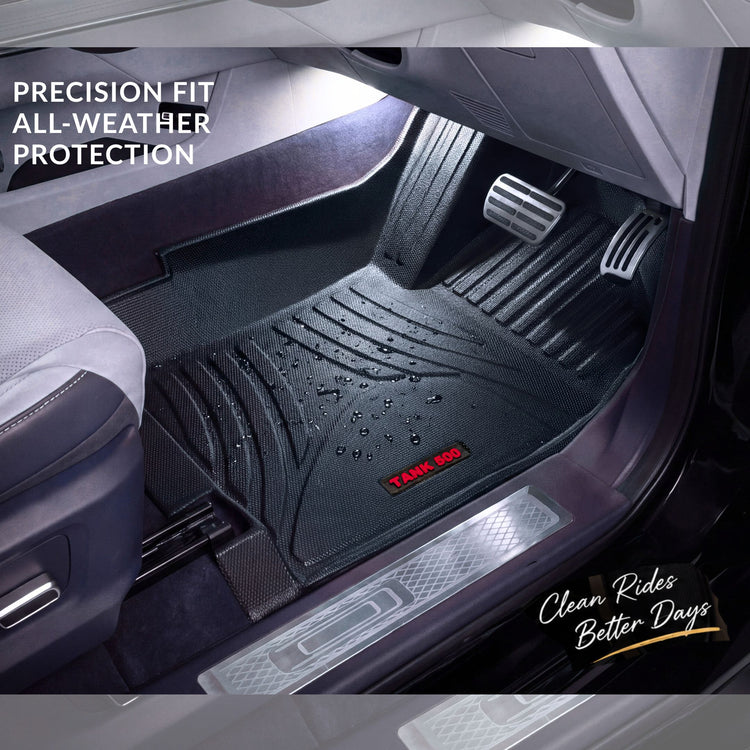 A black rubber car floor mat shown installed inside a vehicle footwell, with the driver's seat and pedals visible. The mat has a textured ribbed design, water droplets on the surface, and a small red badge reading 'TANK 500'. Haseen 9D TPE Car Floor Mats – Custom Fit Heavy Duty Waterproof Car Floor Mats for Cars in Pakistan