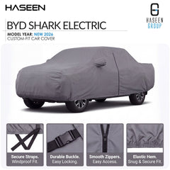 A gray car cover fitted over a sedan on a white background, with HASEEN branding and text reading 'BYD SHARK ELECTRIC' and 'MODEL YEAR: NEW 2026 CUSTOM-FIT CAR COVER.' Four inset detail panels at the bottom show secure straps, a durable buckle, smooth zippers, and elastic hem.