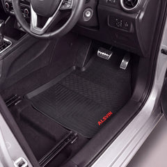 Black Alsin floor mats installed in a car's driver's side footwell, shown with the door open and interior visible.