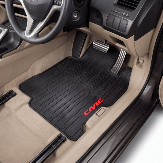 A pair of black rubber car floor mats with red 'CIVIC' branding, shown installed in the front of a beige Honda Civic interior.