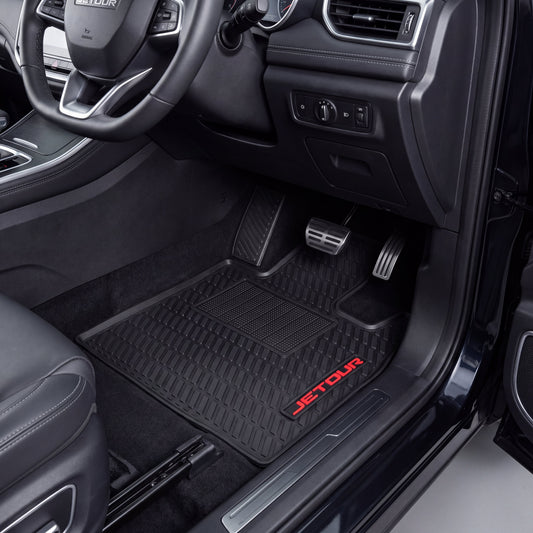 Black car floor mats installed in a vehicle interior, with the driver-side mat showing a red JETOUR logo near the lower edge.