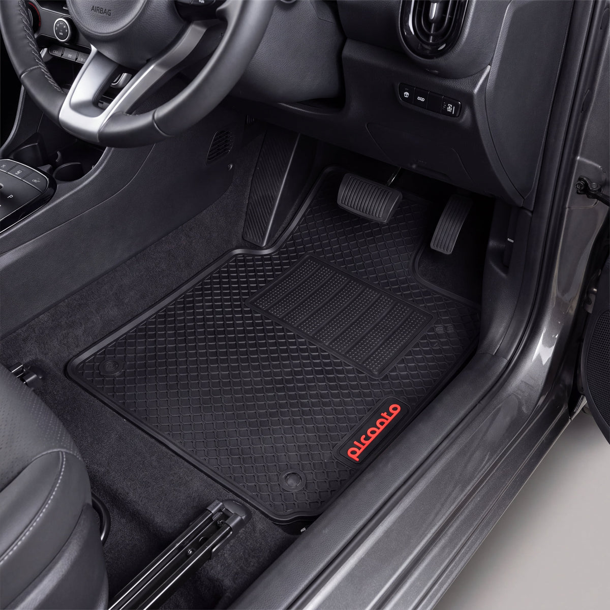 Black rubber car floor mats installed in a vehicle's front footwell, with the driver's seat visible and the brand name 'Picoalo' printed in red on the lower right mat.