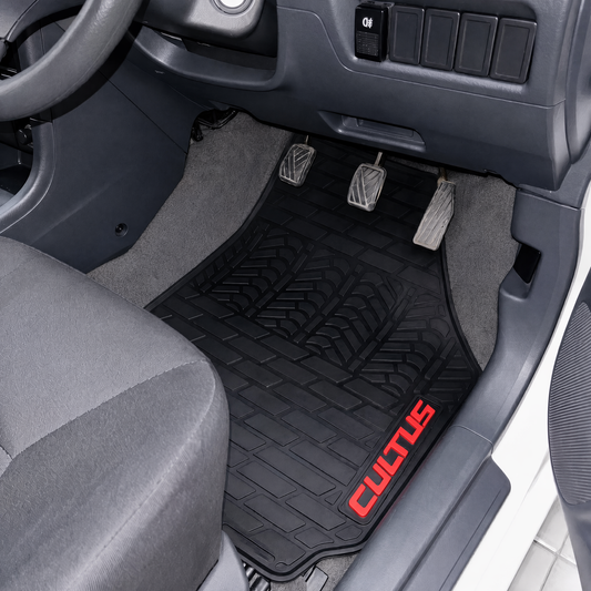 A black textured car floor mat installed in a vehicle's driver's footwell, with gray carpet, pedals, dashboard, and a red CULOTUS logo printed on the lower right corner.