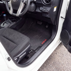 Black car floor mats installed in the front passenger and driver footwells of a white vehicle, with red 'AQUA' branding on the passenger mat.