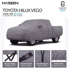 A gray car cover fitted over a Toyota Hilux Vego pickup truck, shown on a white background with Haseen branding and feature callouts for straps, buckle, zippers, and hem.