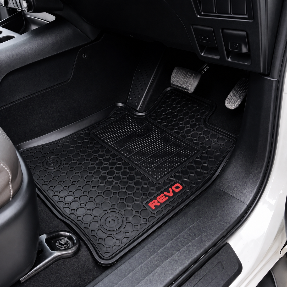 Black textured rubber car floor mat with a red REVO logo, shown installed in a vehicle's footwell.